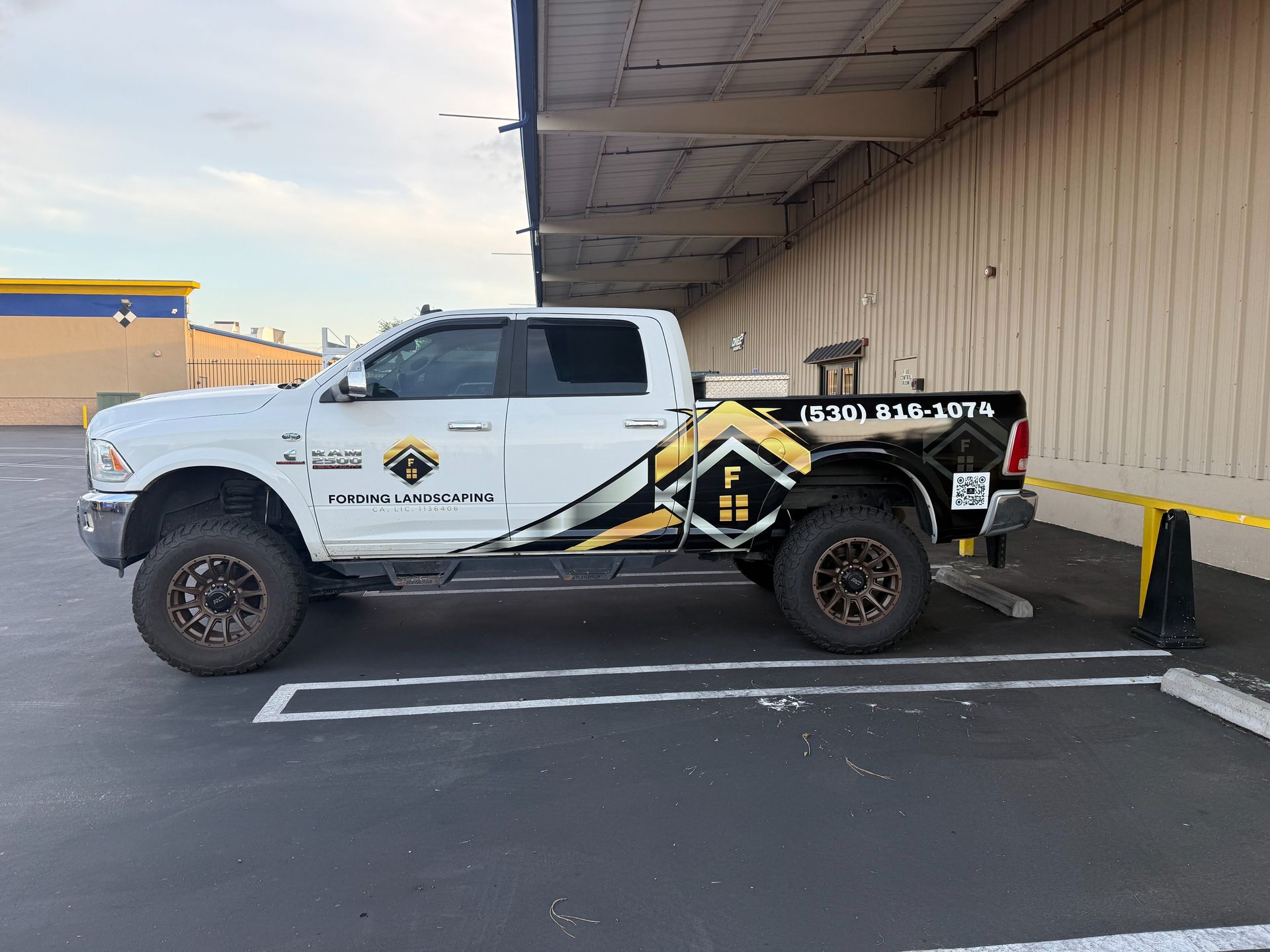 White pickup truck with company decals parked beside a warehouse loading dock at night
