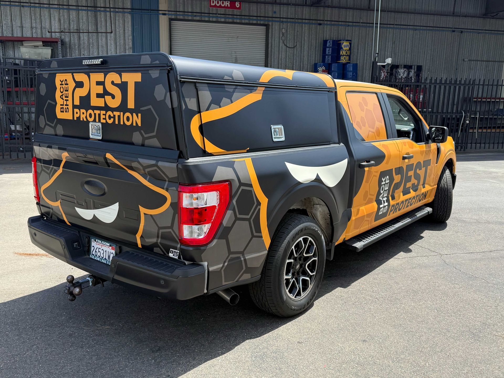 Pest Protection service truck with black-and-orange wrap parked by a warehouse