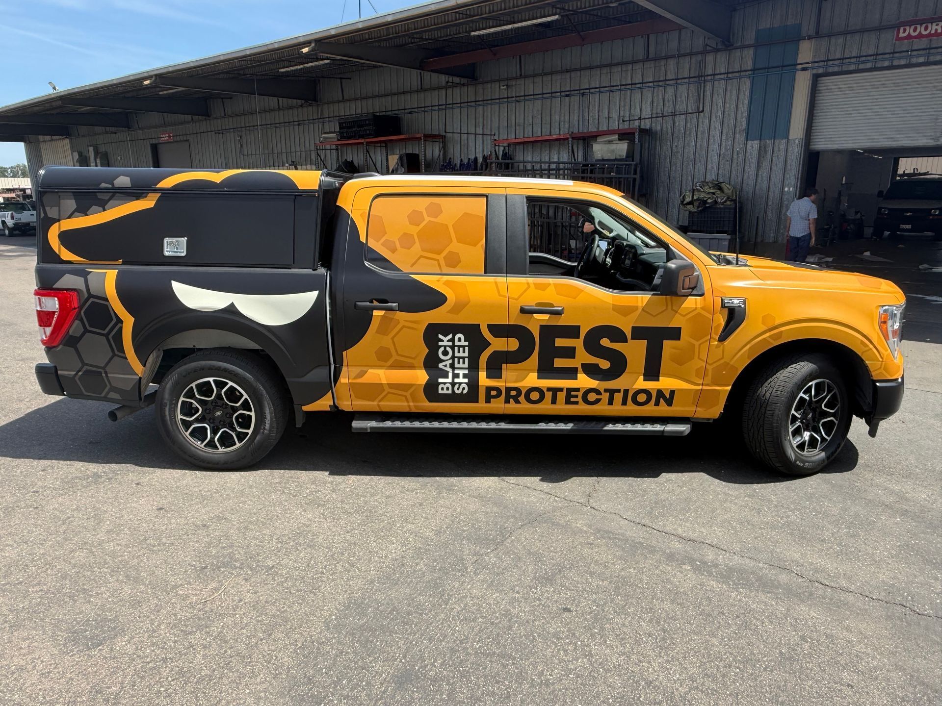 Orange and black pest control truck parked outside a building