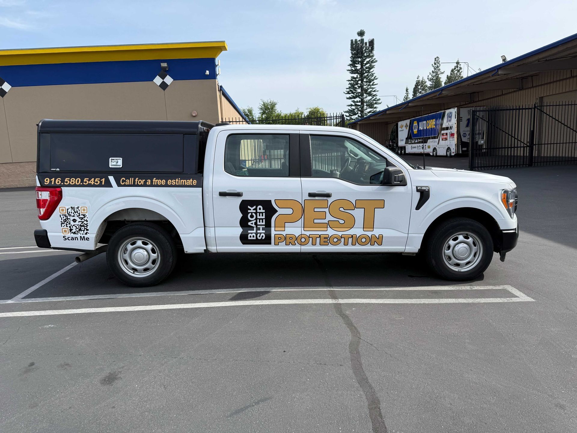 White pest control pickup truck parked in a lot outside a building, side view