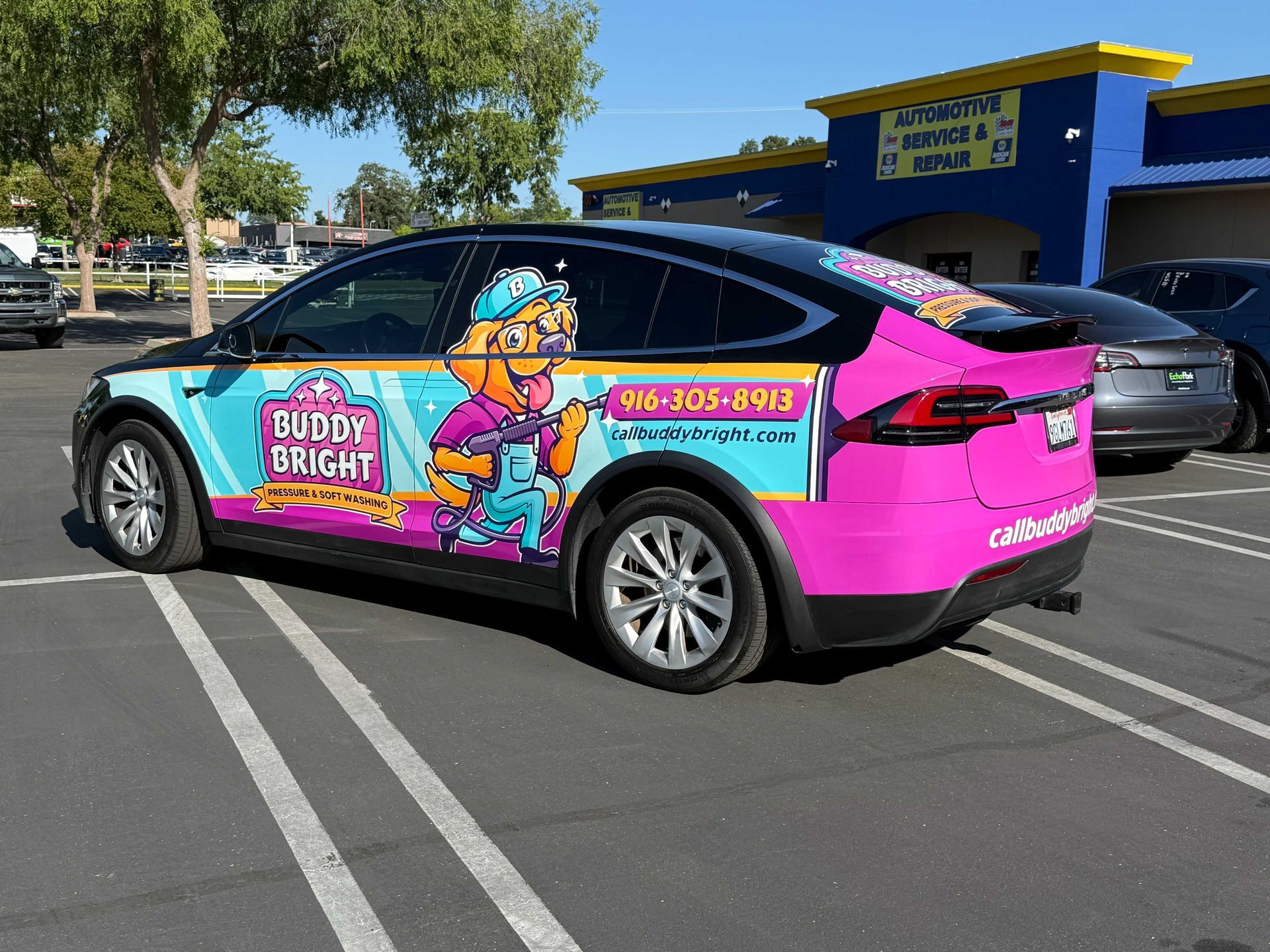 Colorful pink-and-blue Bubble Bright service SUV parked in a lot under a sunny sky