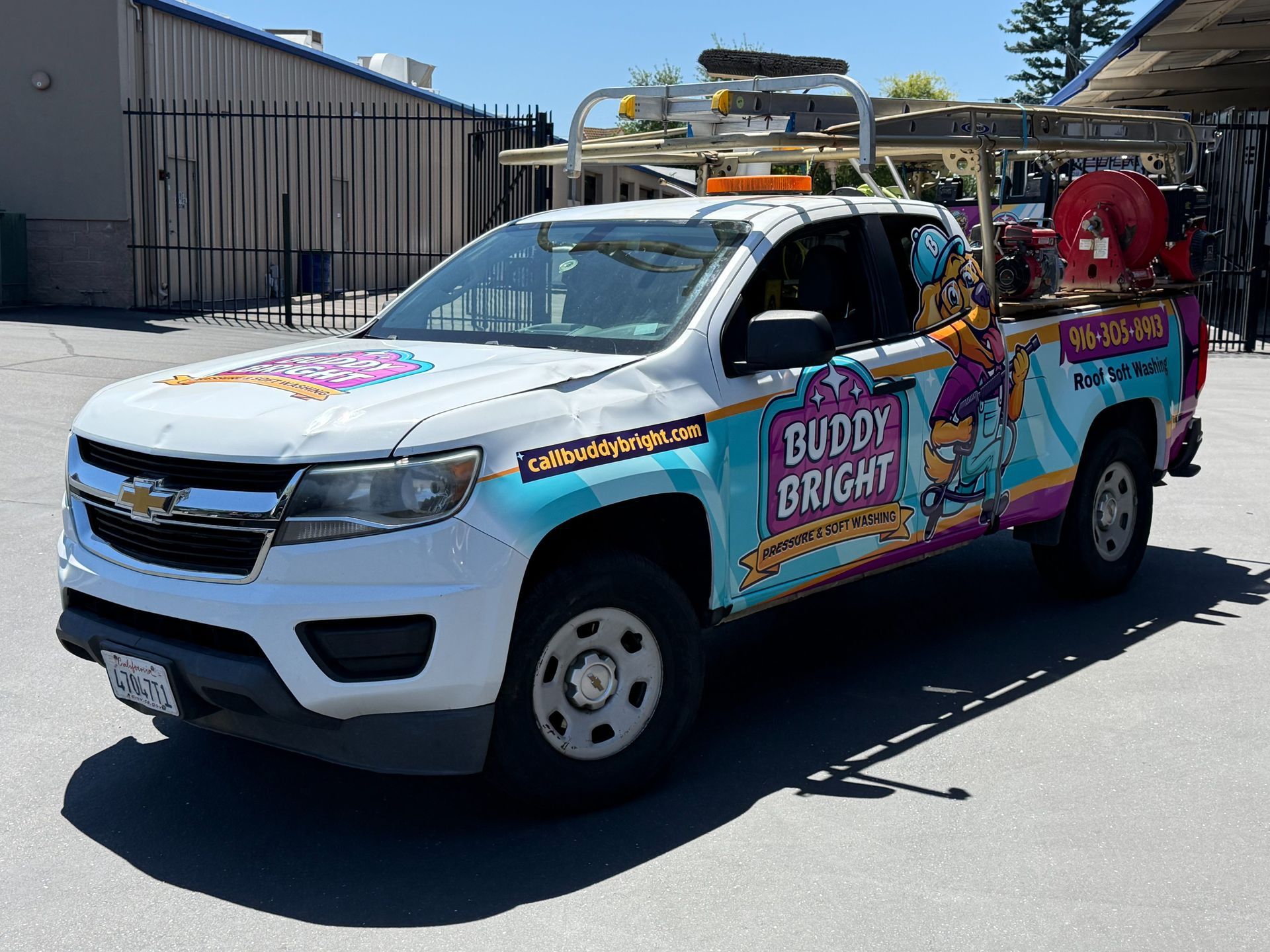 White pickup truck with colorful Buddy Bright signage parked outdoors near a building