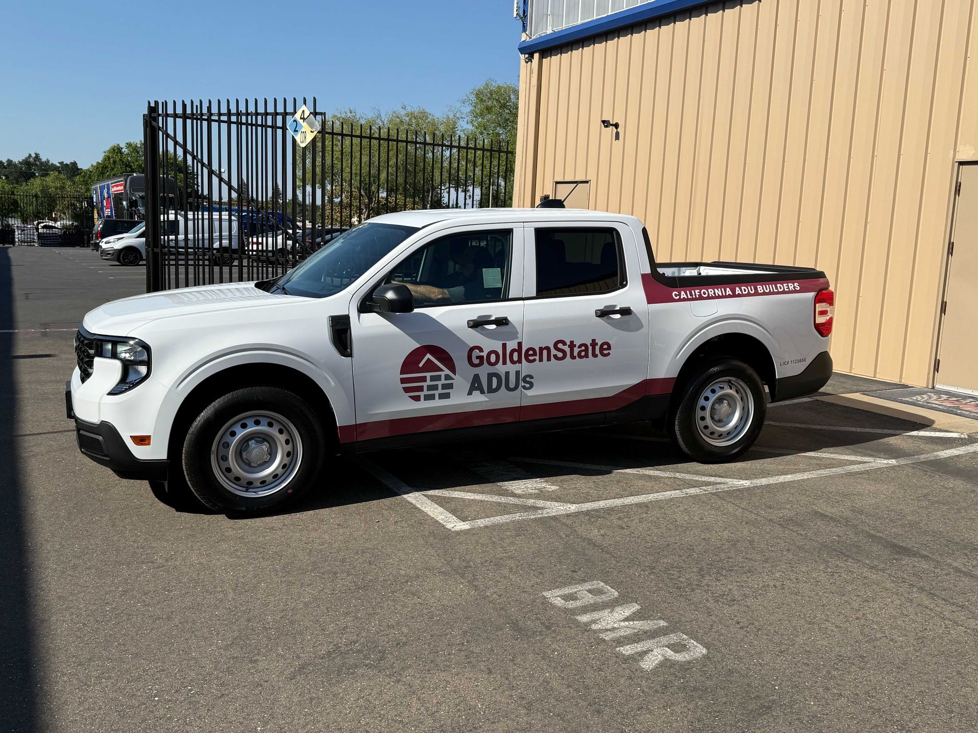 White Golden State ADUs pickup truck parked beside a tan building in a lot.
