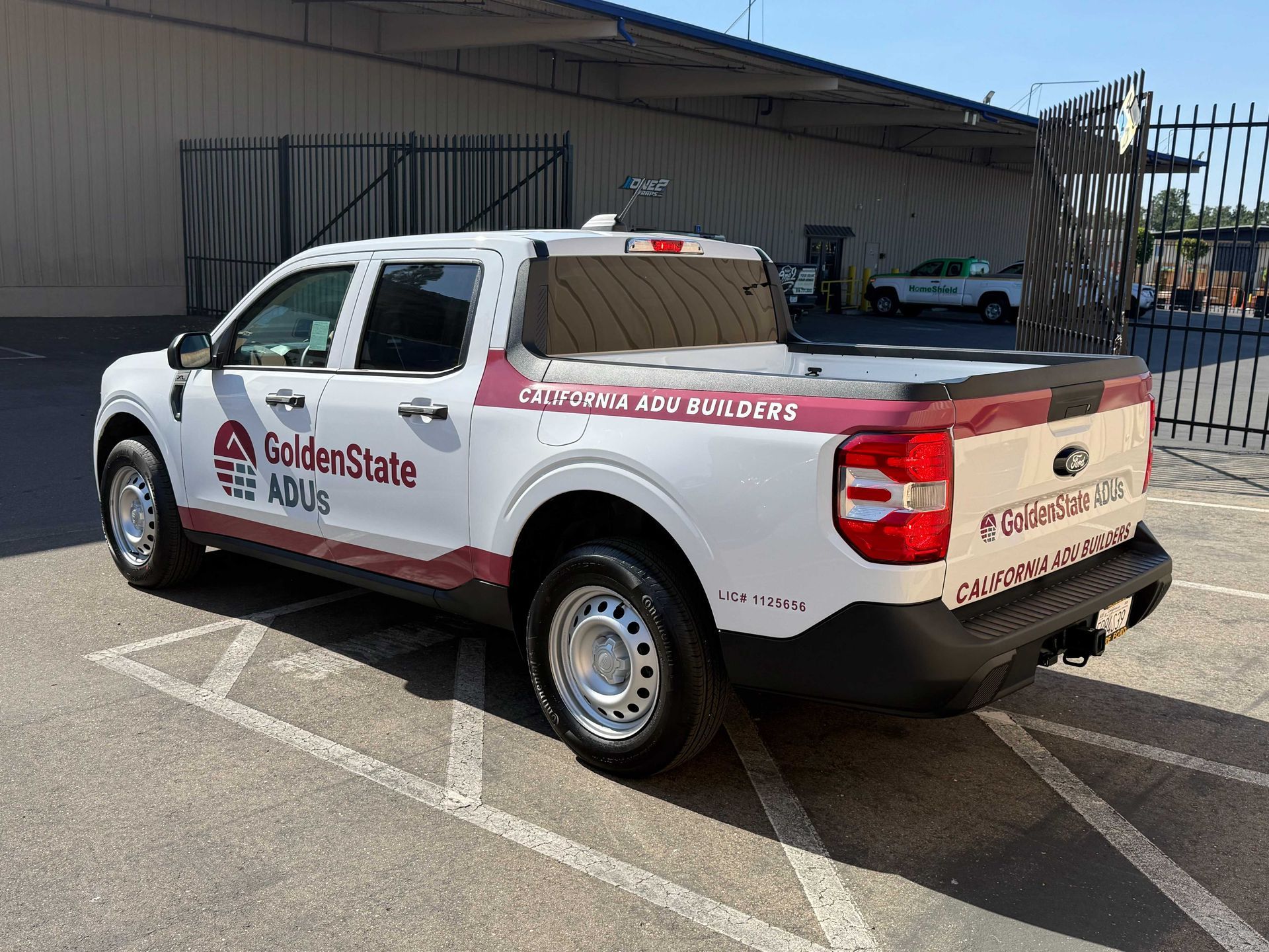 White service pickup truck with red branding and ladder rack parked in an outdoor lot