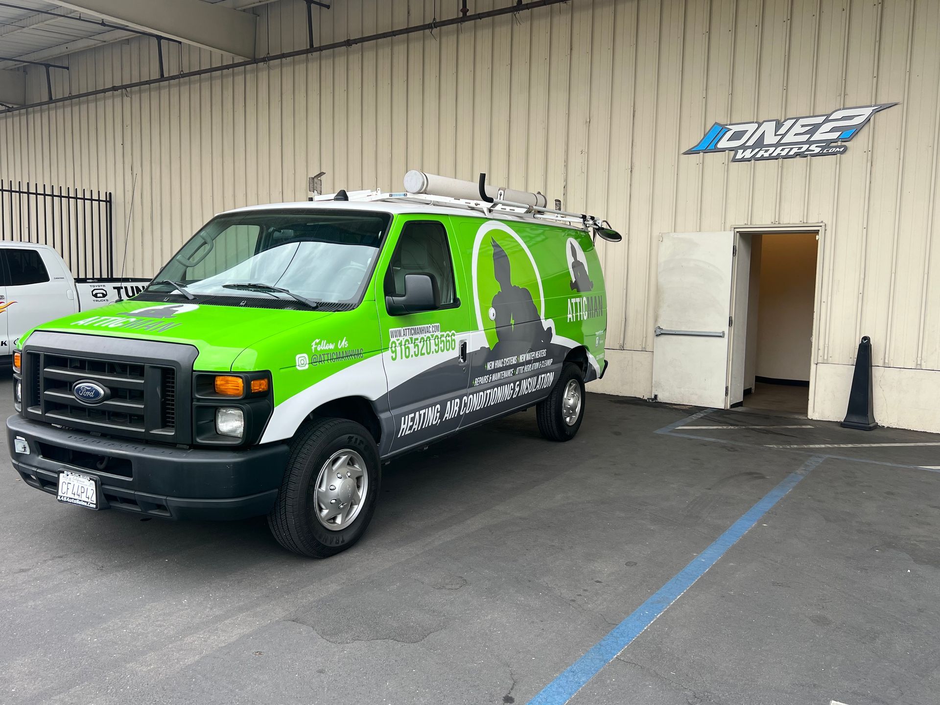a green and white van is parked in front of a building .