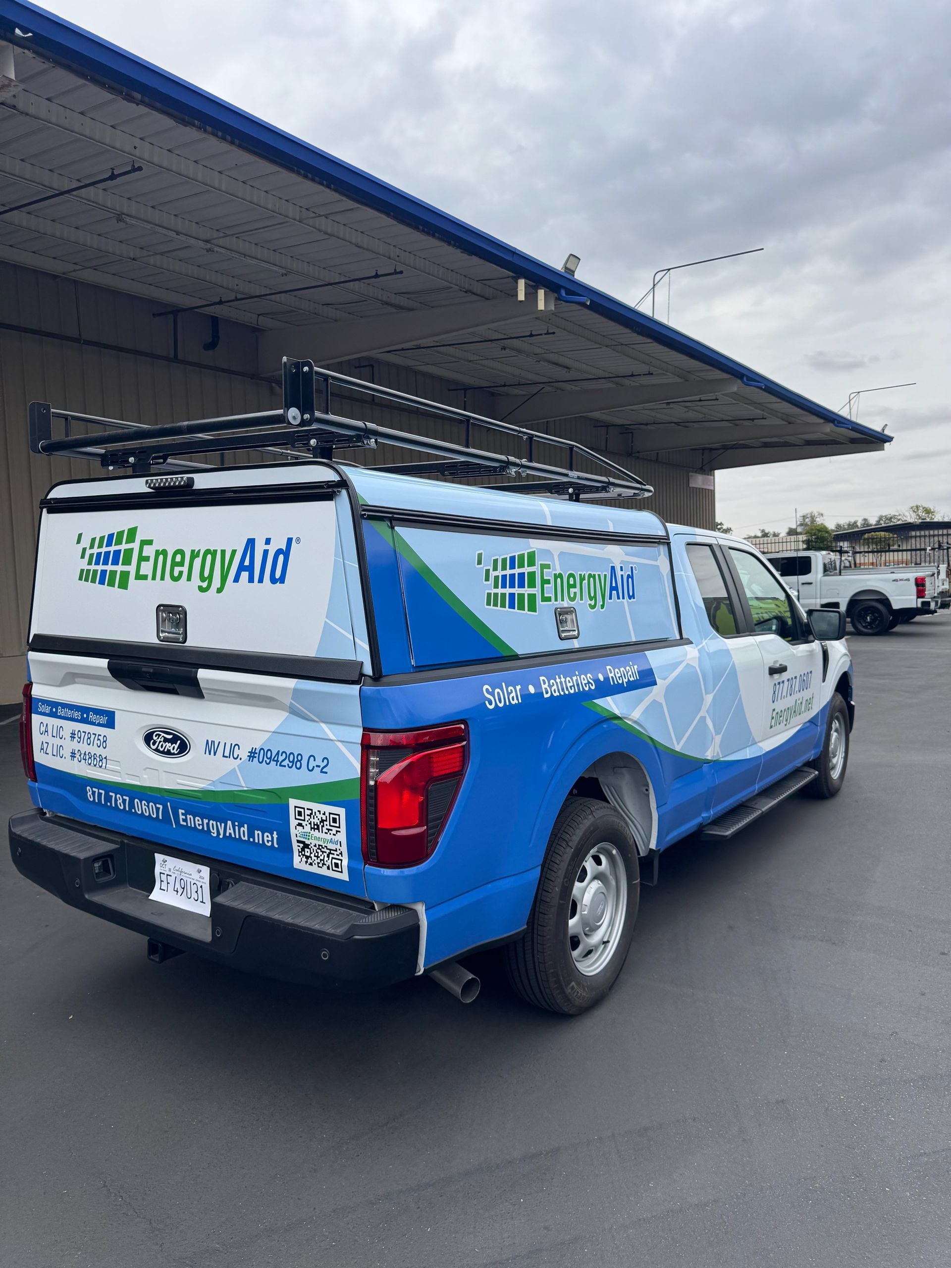 Blue Energy Aid service truck parked under a warehouse awning