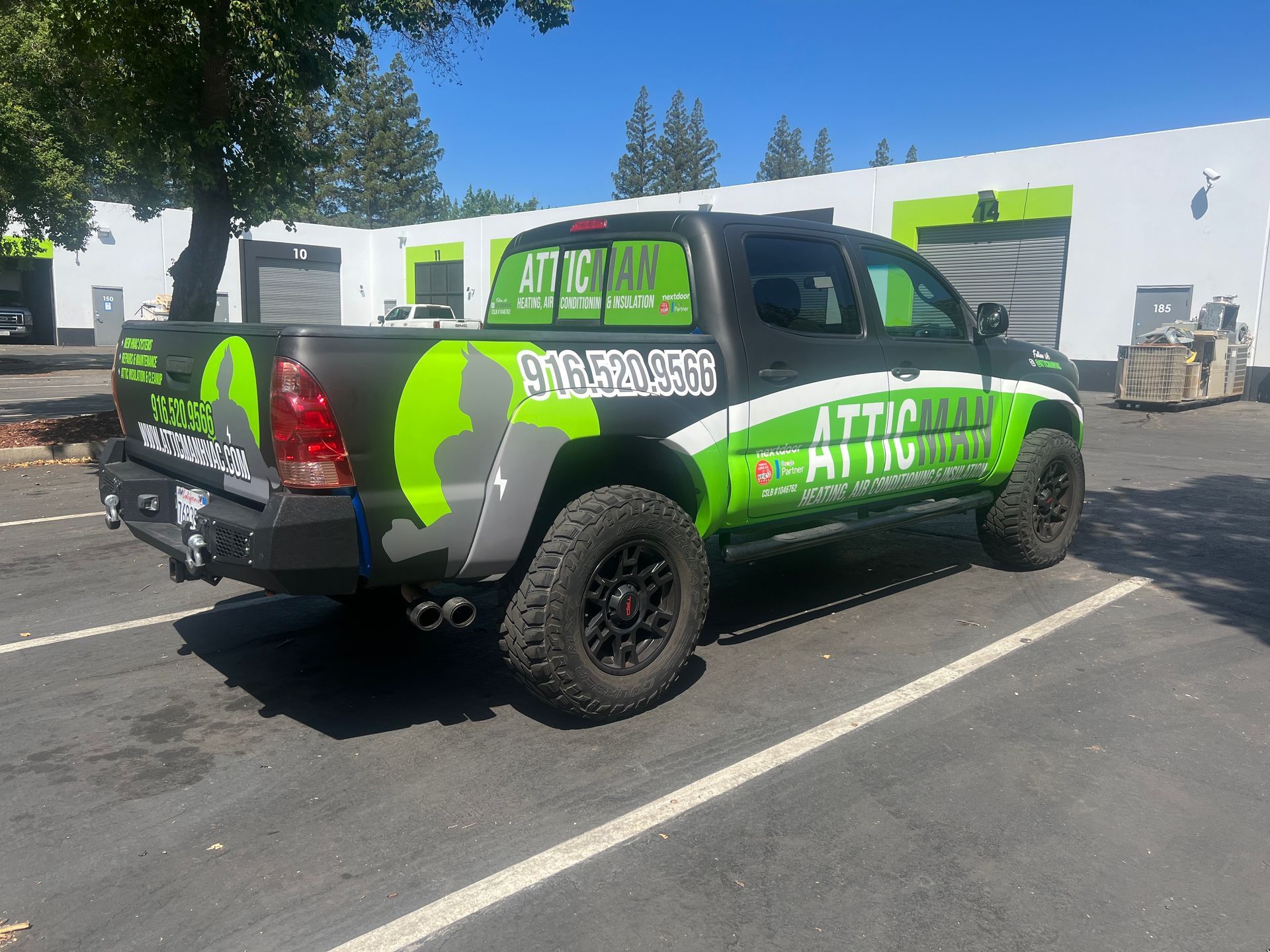 a green and black truck is parked in a parking lot .