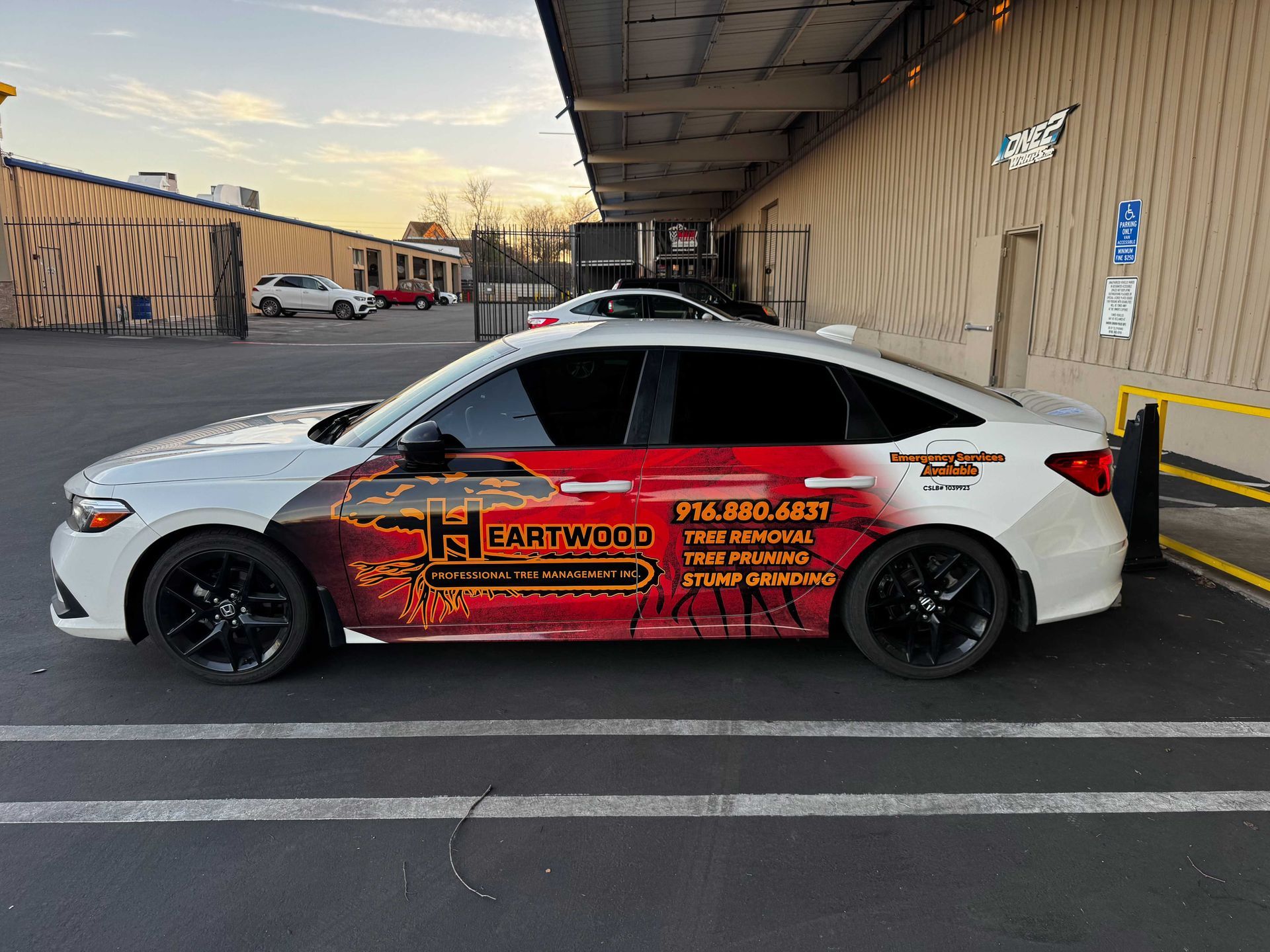 White sports car with red flame decals parked under a covered sidewalk beside a building.