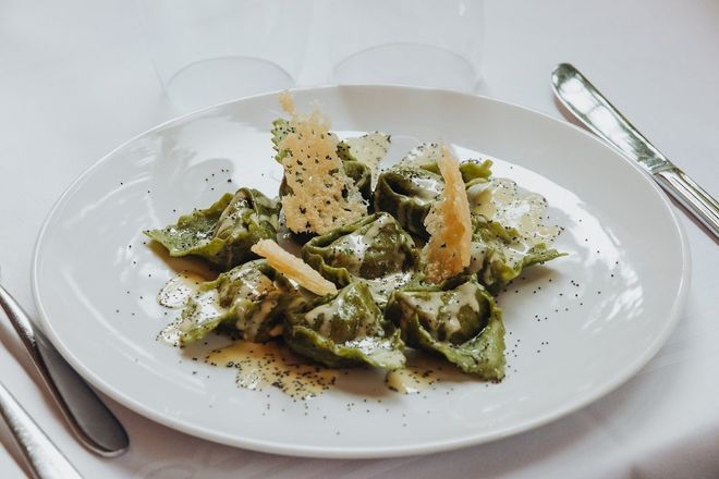 Un bancone di gastronomia che espone vari cibi preparati, con scaffali di vino e altri articoli sullo sfondo.