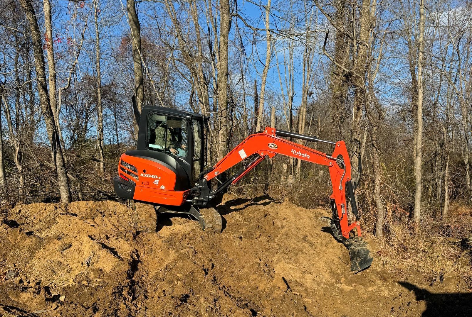 A yellow excavator is sitting on top of a pile of gravel.