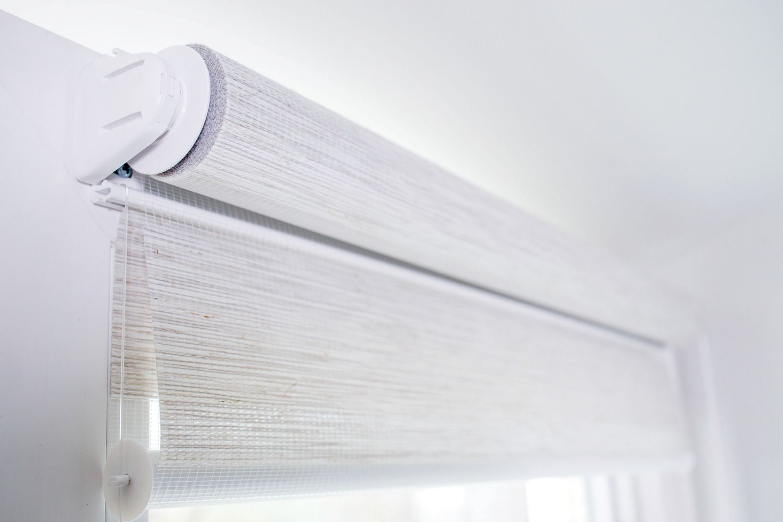 White window blind with top valance on a bright window frame