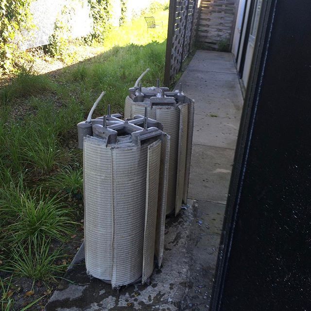 Two pool filters are sitting on a sidewalk next to a building.