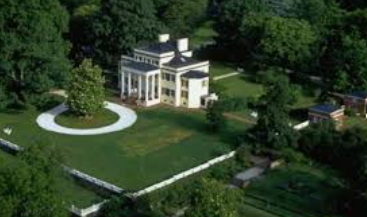 Aerial view of a white house with a green lawn, circular driveway, and surrounding treesAerial view of a white house with a green lawn, circular driveway, and surrounding trees Aerial view of a white house with a green lawn, circular driveway, and surrounding trees