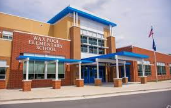 Waxpool Elementary School entrance with brick facade, blue awnings, and flagpole outside. Waxpool Elementary School entrance with brick facade, blue awnings, and flagpole outside.