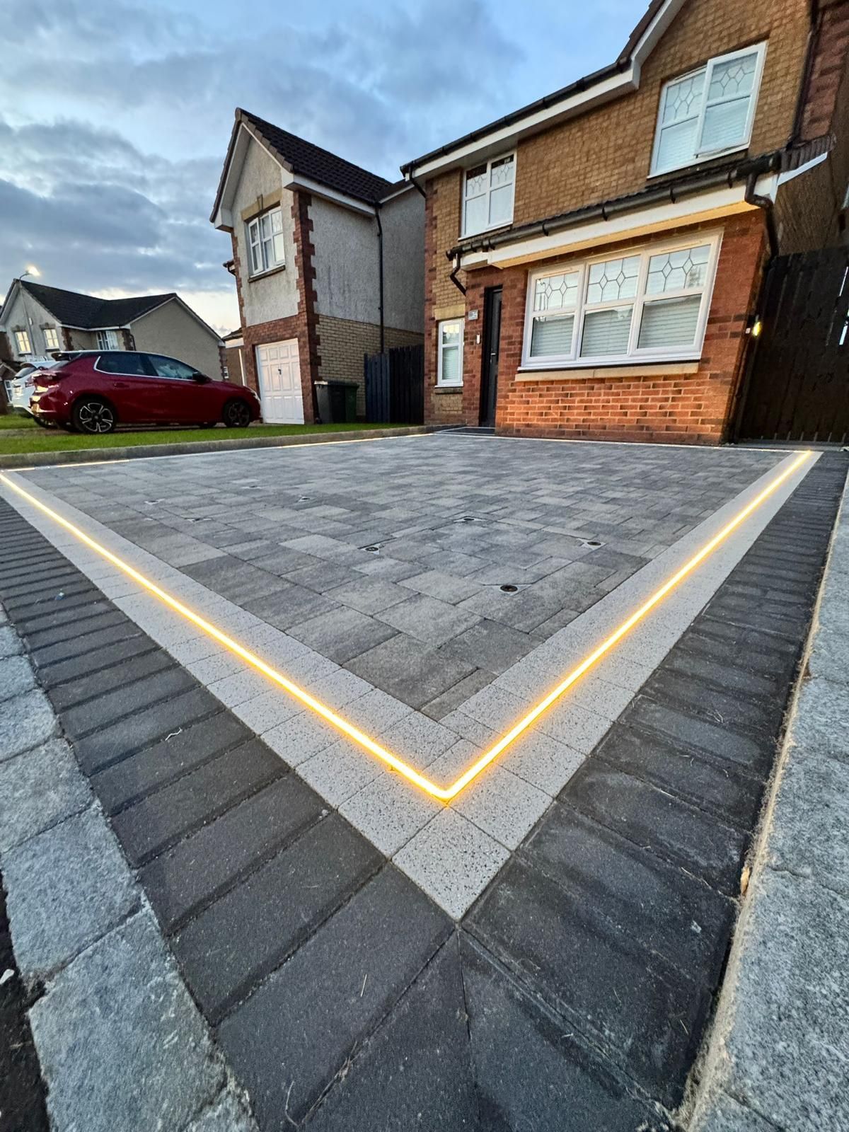 After image of a completed Glasgow monoblock driveway with dark grey block paving, charcoal border, garden lighting and drainage detail