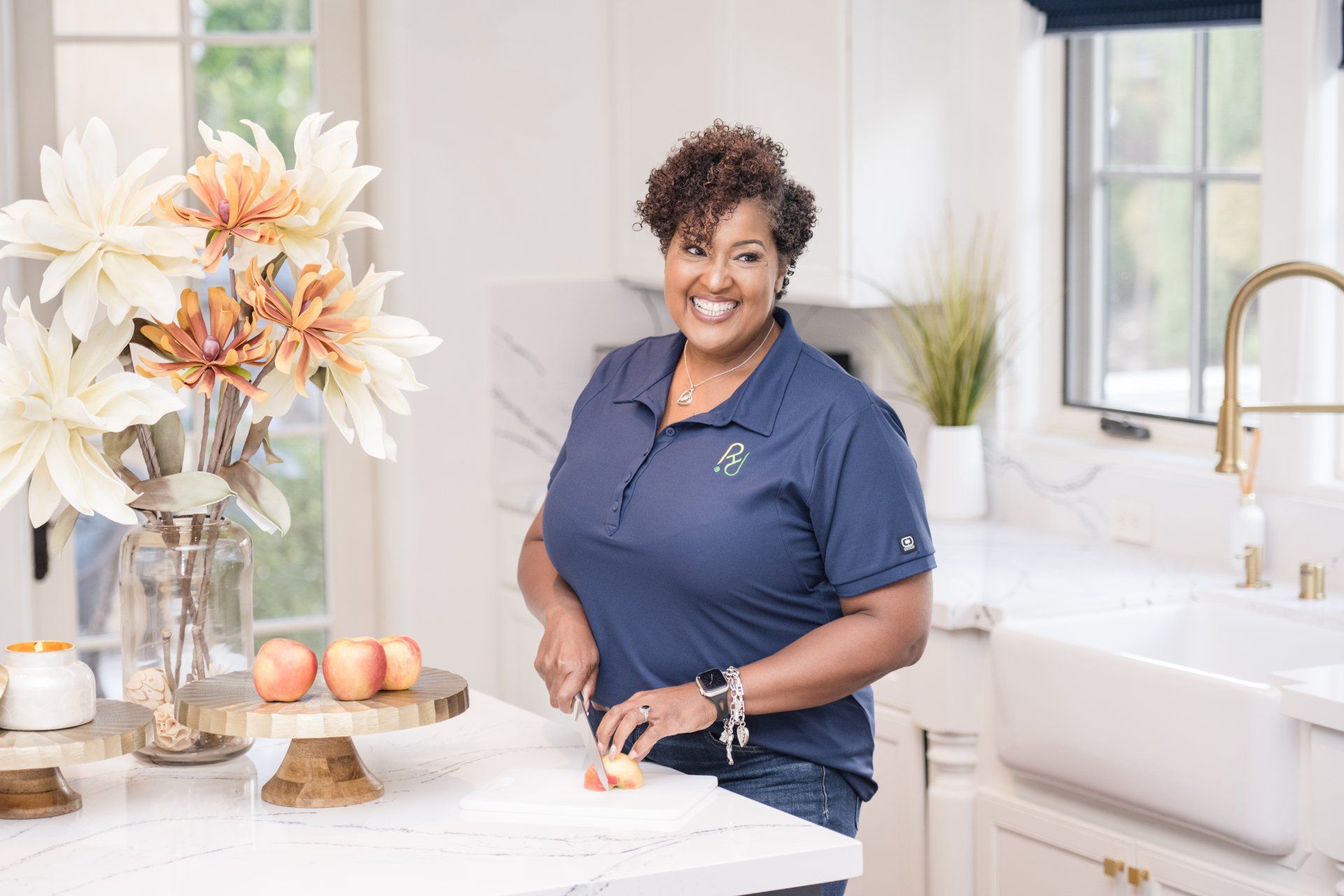 A woman is standing in a kitchen cutting an apple.
