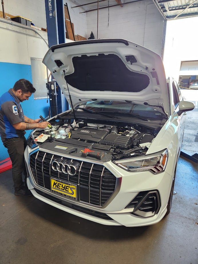 A man is working on the engine of an audi q3 in a garage - Sean's Auto Care