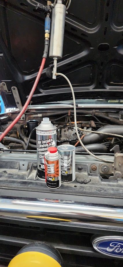 A bottle of spray paint is sitting under the hood of a car.