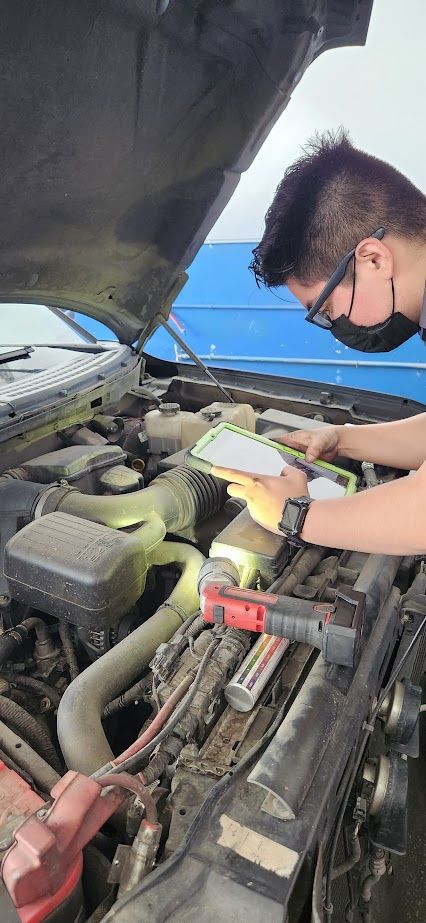 A man is looking under the hood of a car.