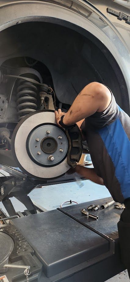 A man is working on the brake system of a car - Sean's Auto Care
