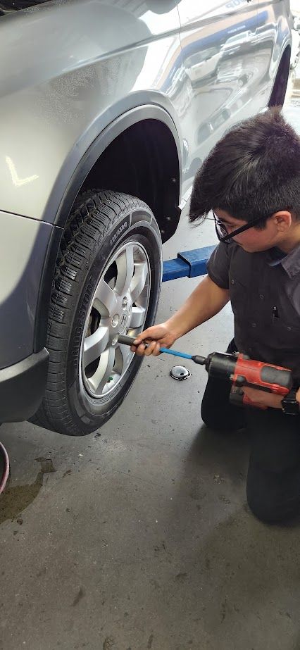 A man is changing a tire on a car in a garage - Sean's Auto Care