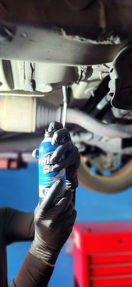 A person is holding a can of spray while working on a car.