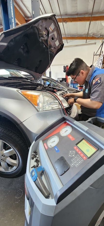 A man is working on a car with the hood up in a garage - Sean's Auto Care