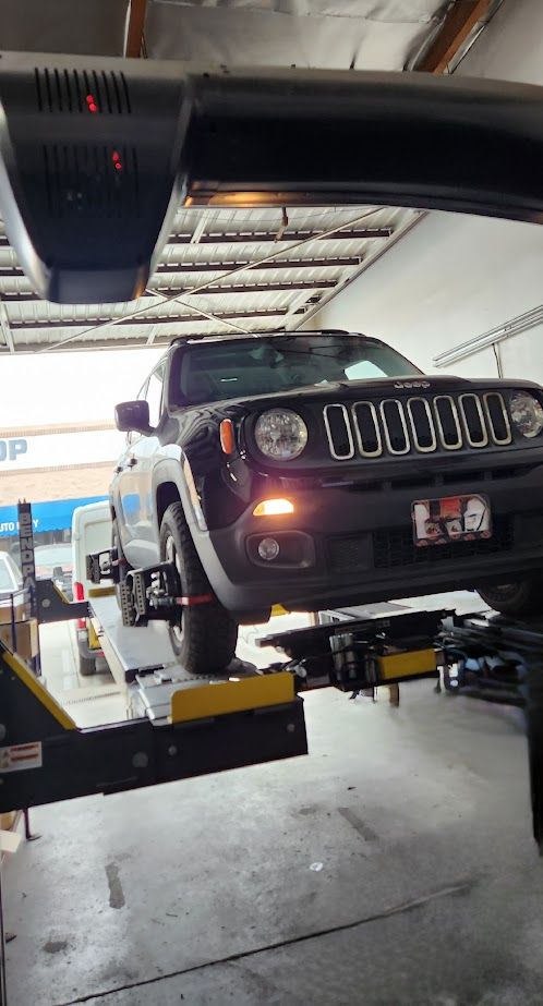 A jeep is sitting on a lift in a garage.