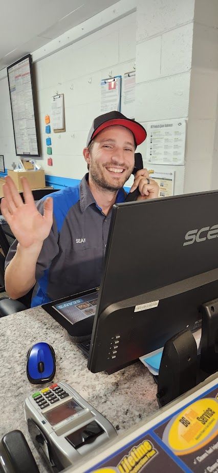 A man is sitting at a counter with a laptop and talking on a cell phone.
