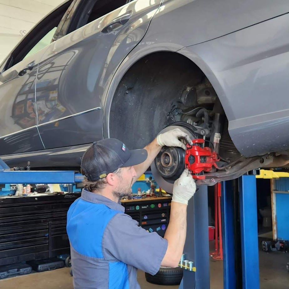 A man is working on the brake caliper of a car