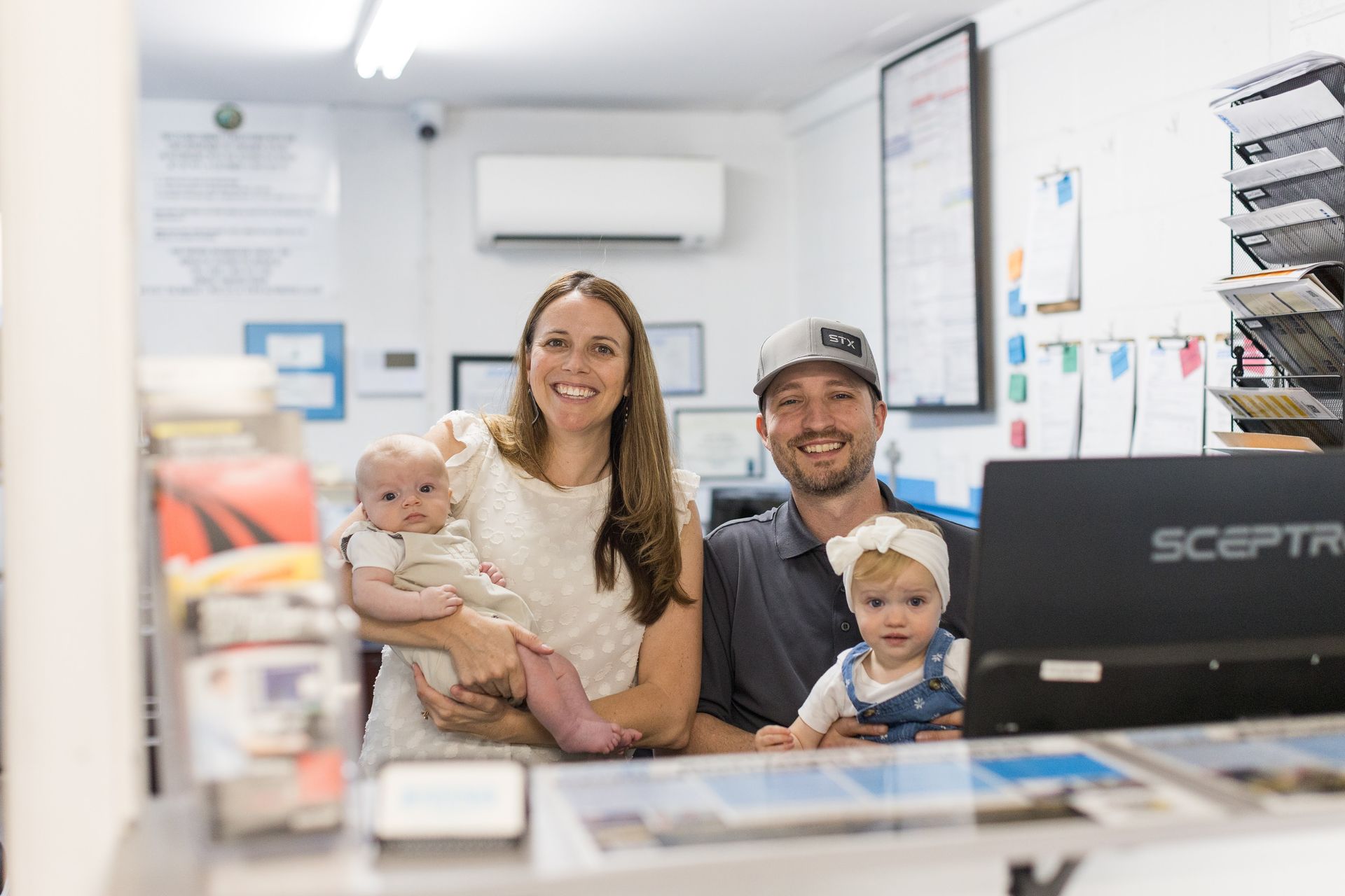 Family smiling behind a front desk in a bright office, with a computer monitor in the foreground | Sean's Auto Care