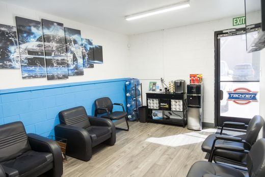 Bright waiting room with black chairs, blue wall, wood floor, and glass door | Sean's Auto Care