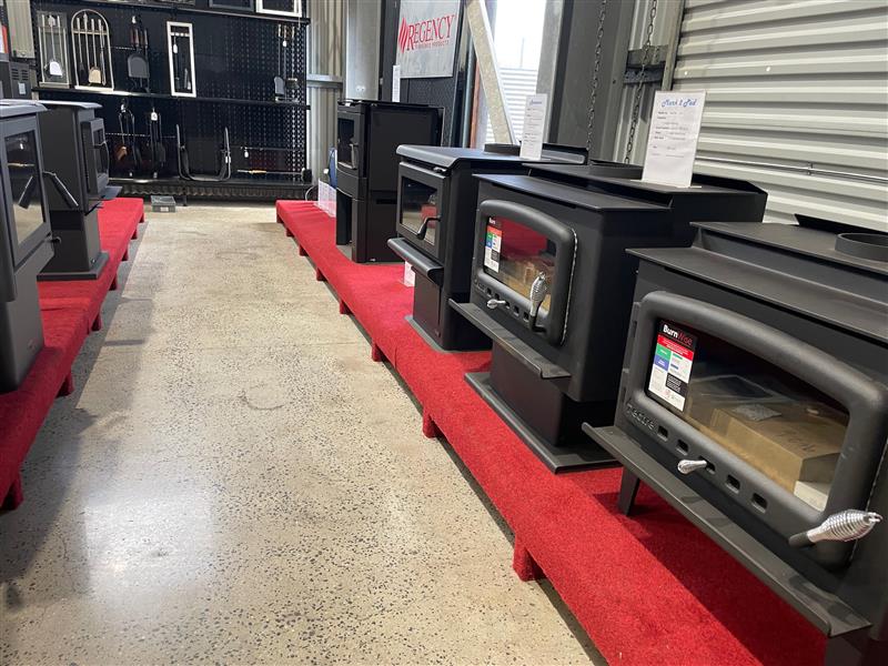 A Row of Wood Stoves Are Lined Up on a Red Carpet in a Store — Tolga Traders in  Tolga, QLD