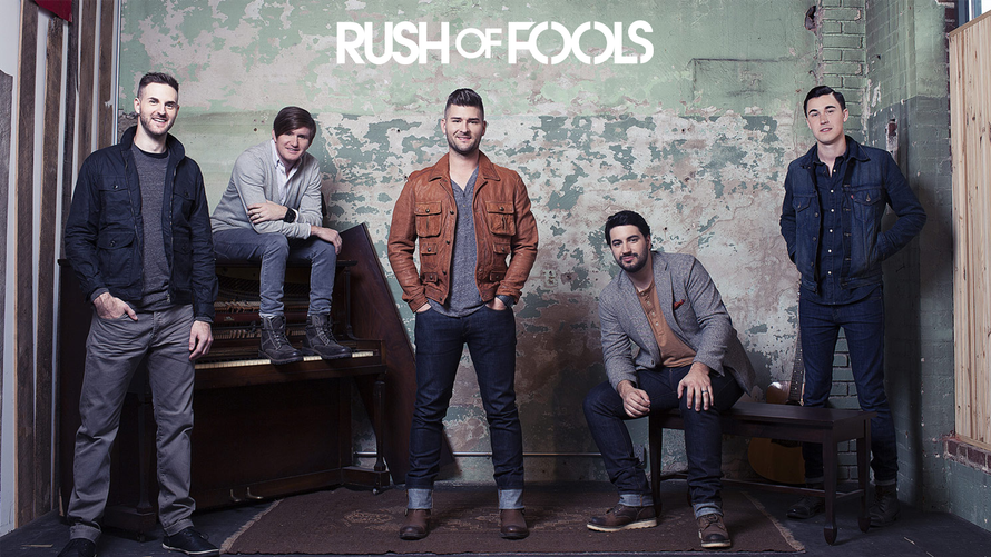 Five men pose against a concrete wall with the title “Rush of Fools” above them.