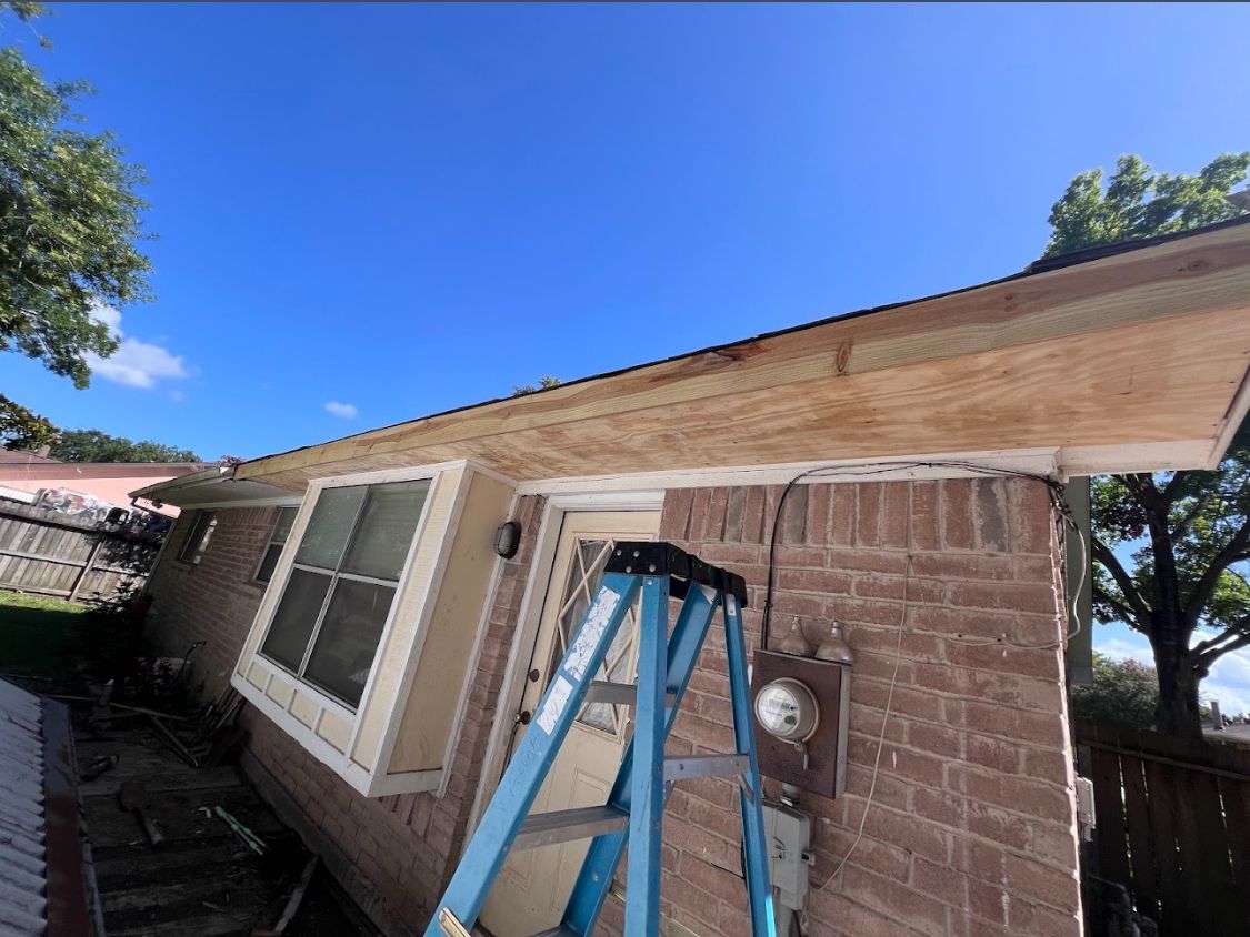 Blue ladder leaning against house exterior near a window and wooden fence under clear sky