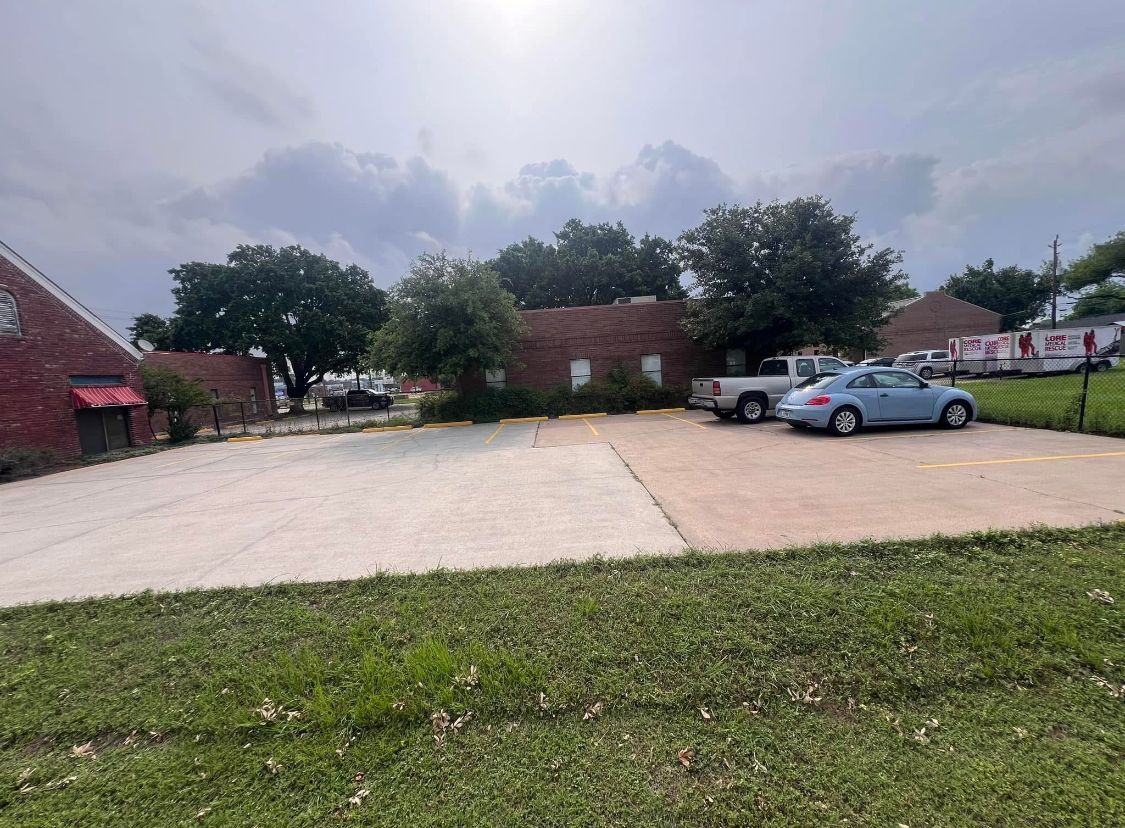 Parking lot with a silver car beside brick buildings under a cloudy sky