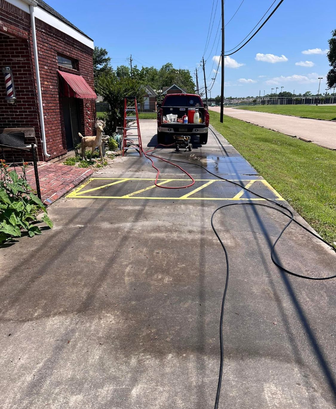 Black SUV beside a brick building with yellow caution tape blocking a wet driveway by the road