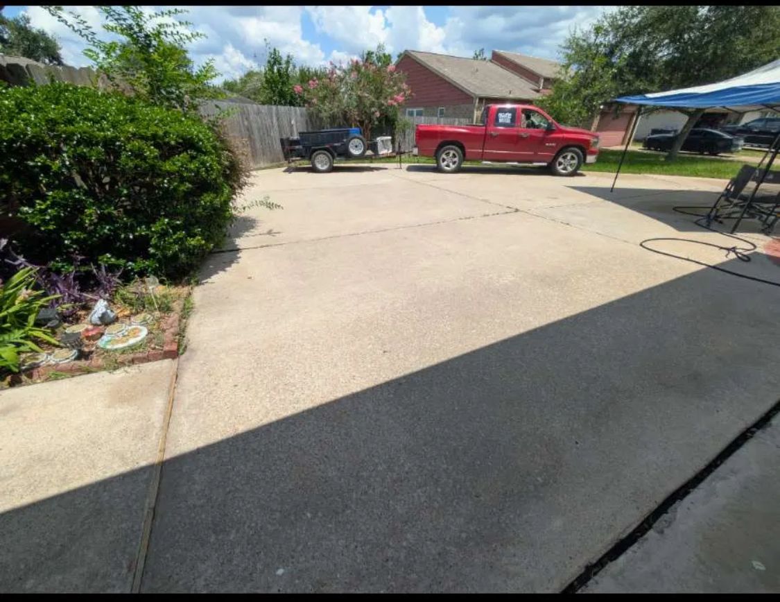 Driveway with a red pickup truck and black trailer near a house on a sunny day.