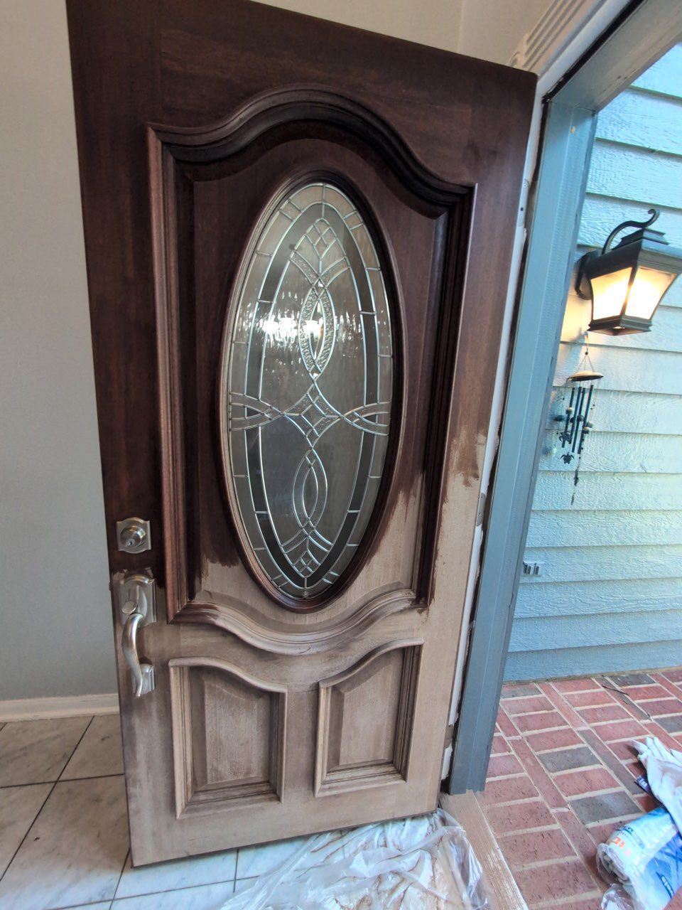 Open front door with ornate oval glass panel, slightly ajar at a house entrance.