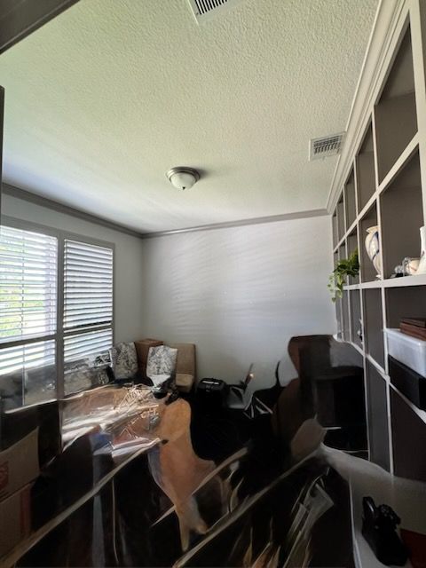Small office with desks, chairs, shelving, and blinds covering a window.