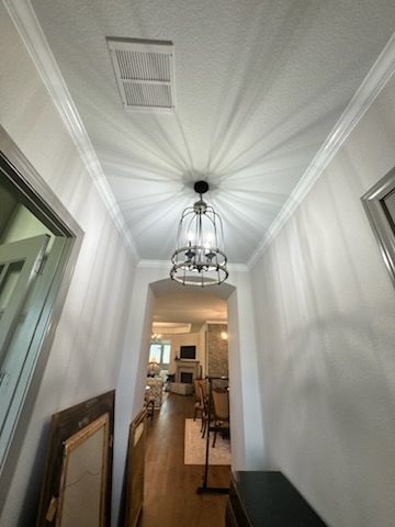 Narrow white hallway with hanging lantern light and framed art, leading into a dining room