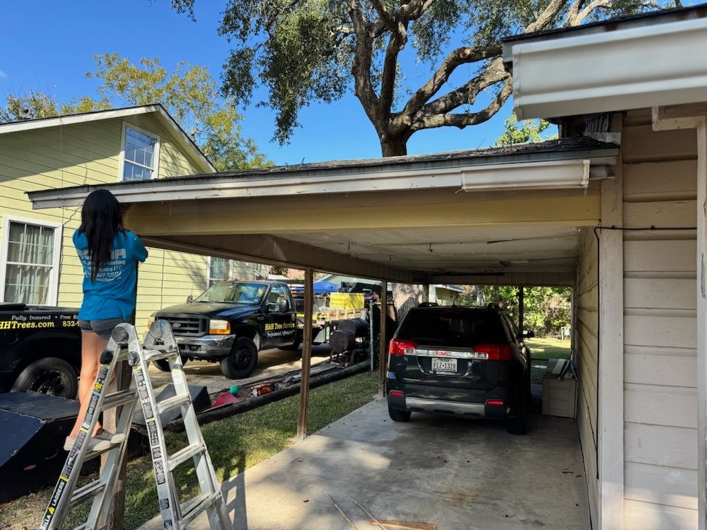 Person on a ladder installing a beige carport roof beside a parked black SUV on a sunny day