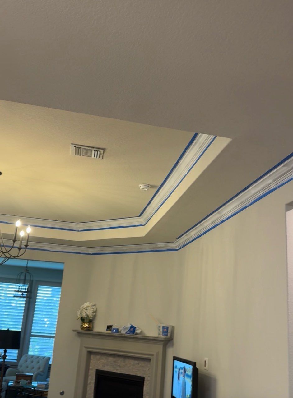 Living room with tray ceiling, blue accent trim, fireplace mantel, and TV