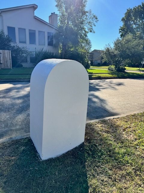 White utility box on a grassy roadside near a suburban house on a sunny day
