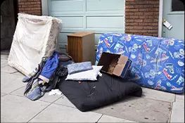 A pile of junk on the sidewalk in front of a garage.