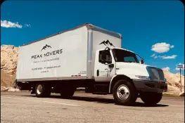 A white moving truck is parked on the side of the road.