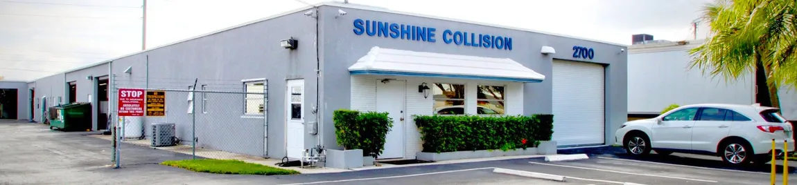 A car is parked in front of a building that says sunshine collision.