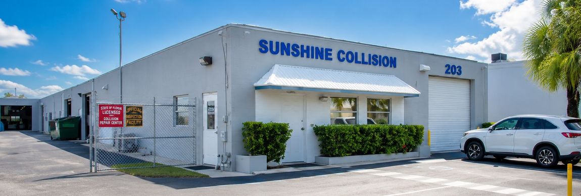 Sunshine Collision auto body shop with white exterior and parked cars outside