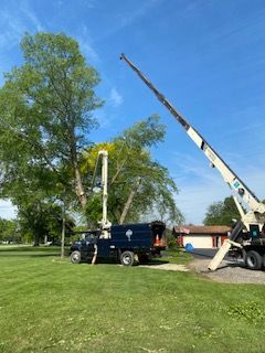A truck with a crane attached to it is parked in a grassy field.