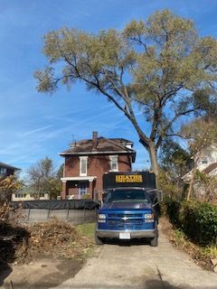A blue truck is parked in front of a brick house.